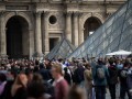 Des visiteurs, en avril 2022, devant la pyramide du Louvre, à Paris. AFP