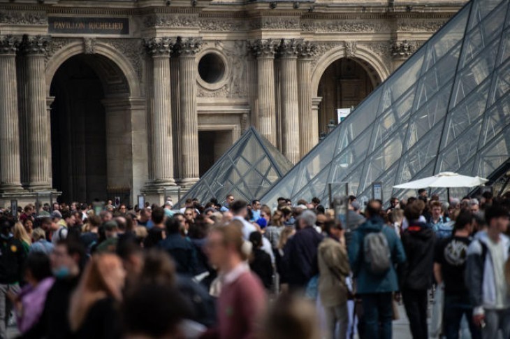 Des visiteurs, en avril 2022, devant la pyramide du Louvre, à Paris. AFP